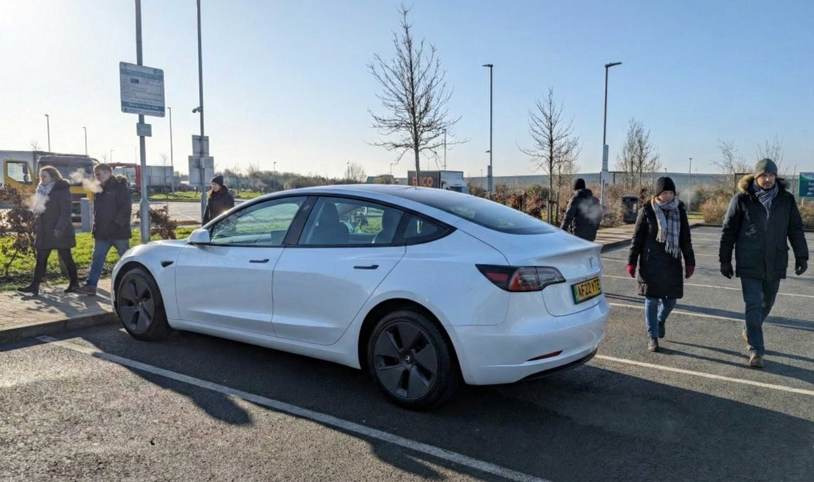 White Tesla Model 3 electric taxi stopped at a service station during a long-distance transfer from Criccieth to Bedford.